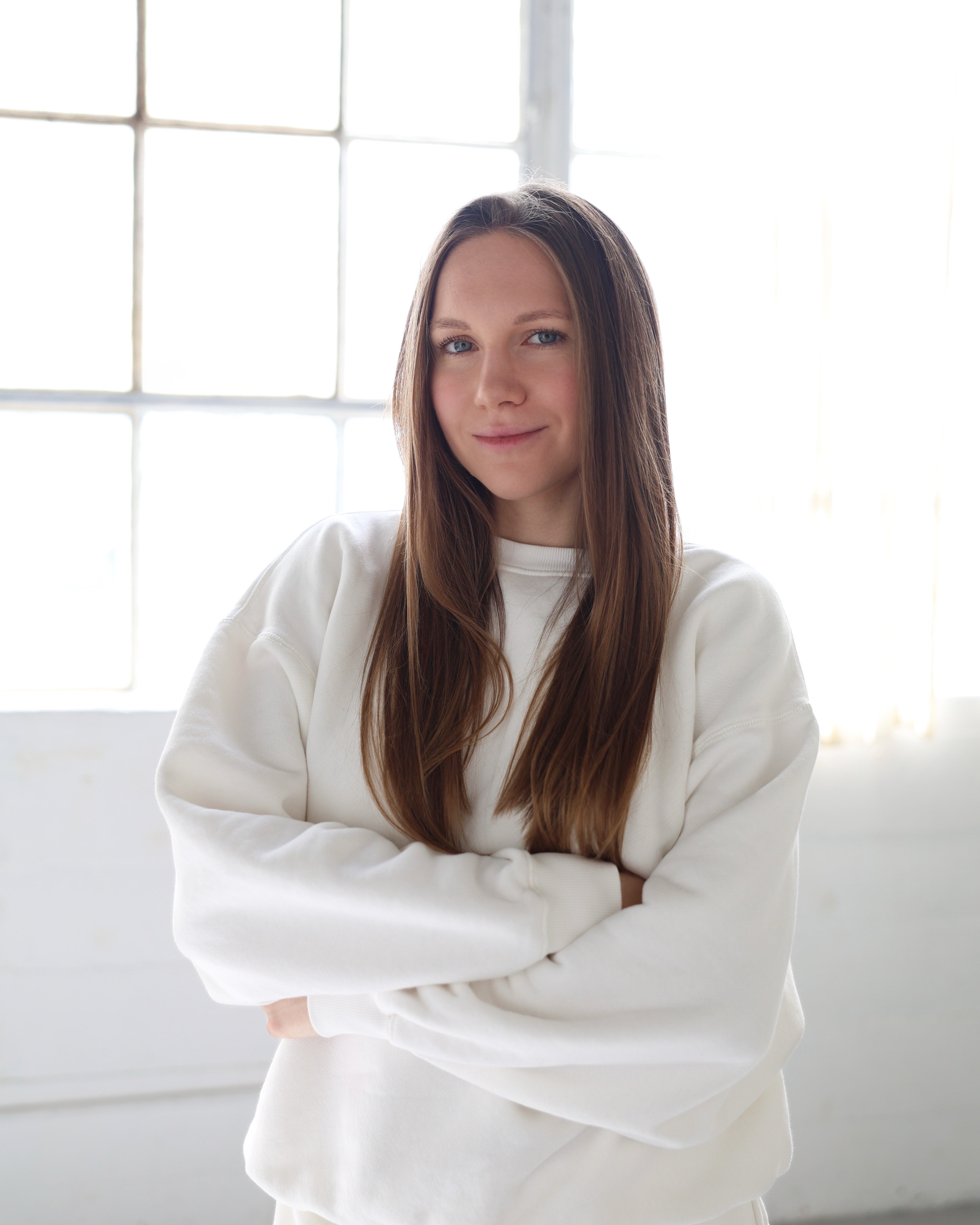 Founder of My Way Journals standing in natural light, wearing a soft white outfit with arms crossed, minimal and bright portrait.